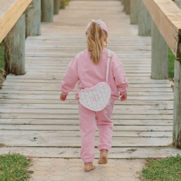 Toddler in pink outfit walking on wooden pathway.