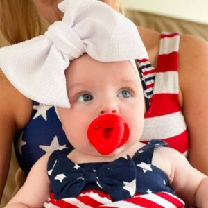 Baby in patriotic outfit with large white bow.