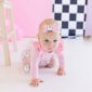 Baby in pink crawling with ghost-themed outfit.
