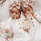 Two-month-old twins with pacifiers and bows.