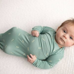 Baby in green swaddle on white blanket