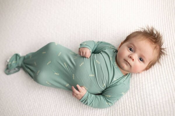 Baby in green swaddle on white blanket