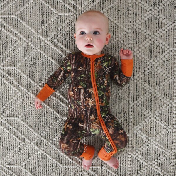 gigi and max hunter camo zip sleepies little bamboo baby outfit Baby in camouflage pajamas on patterned rug.