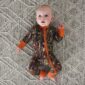 Baby in camouflage pajamas on patterned rug.