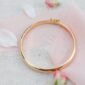 Golden bracelet on pink fabric with flower petals.
