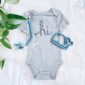 Gray baby onesie with 'hi' text and baby toys.