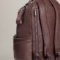 Brown leather backpack with side pockets and zippers.