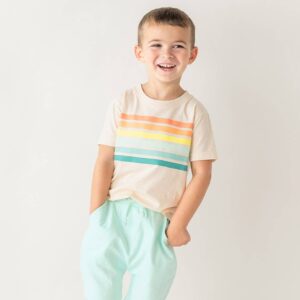 Smiling child wearing striped shirt and mint pants.