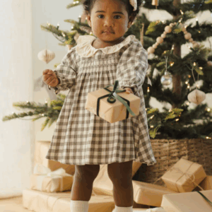 Child with gift near decorated Christmas tree.