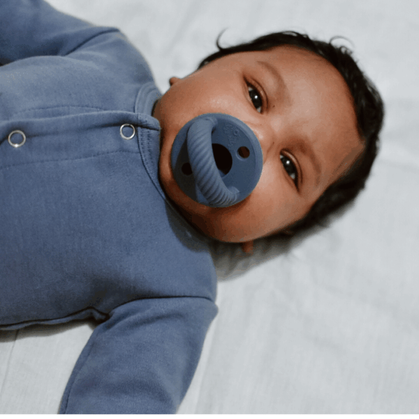itzy ritzy sweetie soother™ pacifier sets (2 pack): agave + succulent cables Baby in blue onesie with pacifier