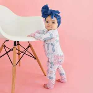 Baby in blue bow standing by chair