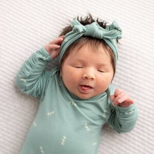 Sleeping baby in green outfit and headband.