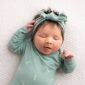 Sleeping baby in green outfit and headband.