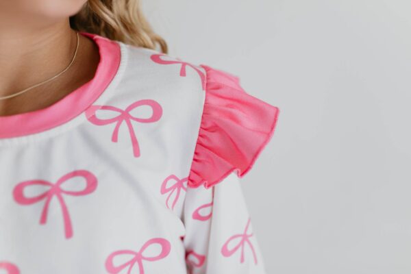 Pink bow-patterned dress with ruffle sleeve detail.
