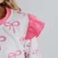 Pink bow-patterned dress with ruffle sleeve detail.