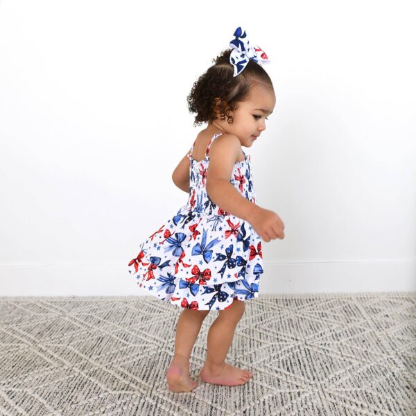gigi and max eleanor bow clip bow 4th of july hair accessory Toddler in butterfly dress walking indoors.