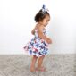 Toddler in butterfly dress walking indoors.