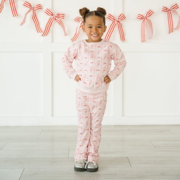 Child in pink pajama set with red bows.