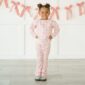 Child in pink pajama set with red bows.