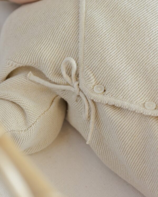 quincy mae wrap knit footie heathered natural cream with matching hat Beige knit fabric with buttons and ties.