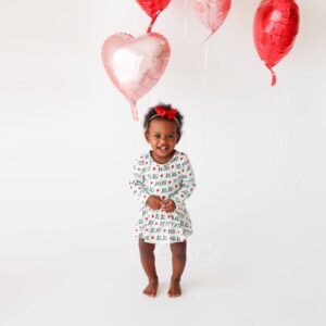 Child smiling with heart balloons.