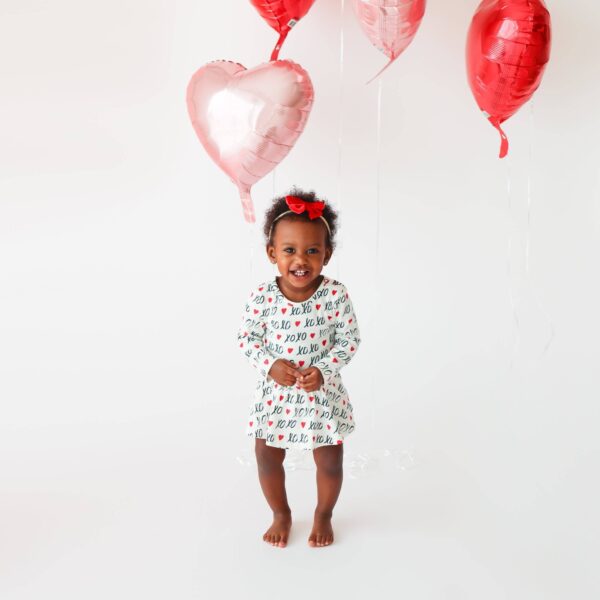 molly and max lola & taylor baby girls cotton charlotte dress xoxo Child smiling with heart balloons.