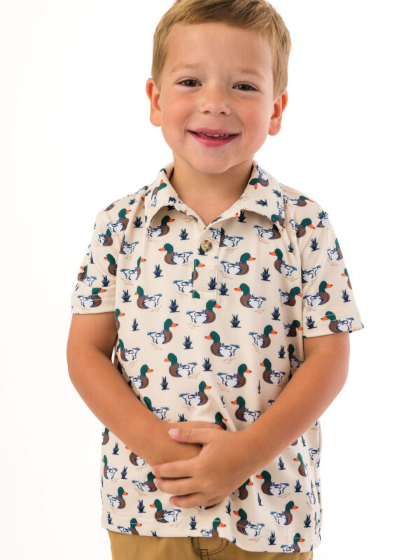 Child wearing duck pattern polo shirt smiling