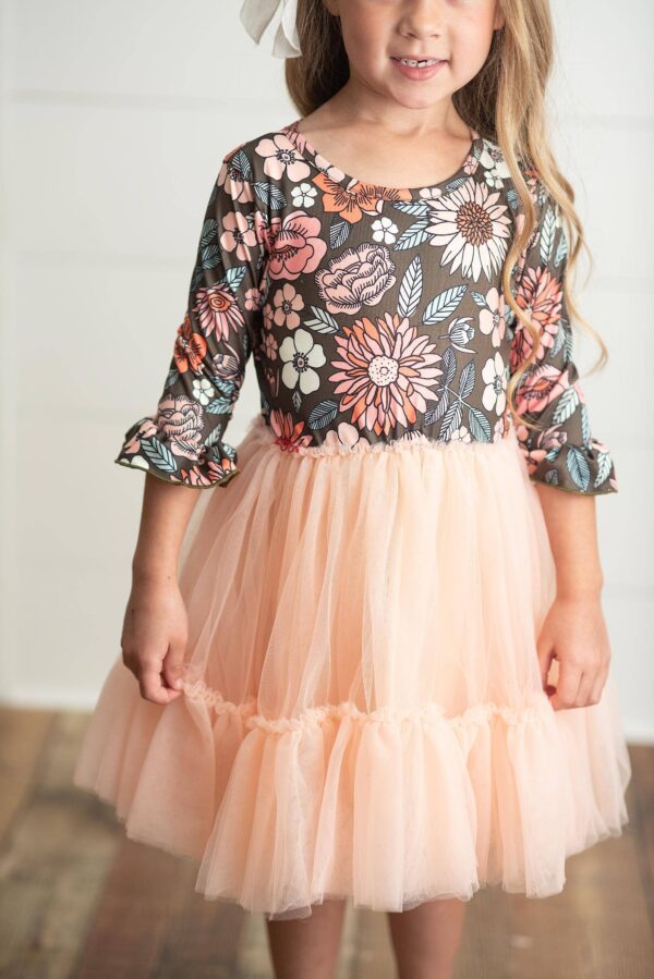 Child wearing floral dress with pink tulle skirt.