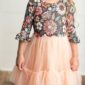 Child wearing floral dress with pink tulle skirt.