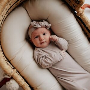 Infant in beige outfit lying in basket