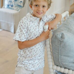 Smiling child stands by bed in bright room.