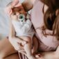 Baby with pacifier and bow, held by woman.