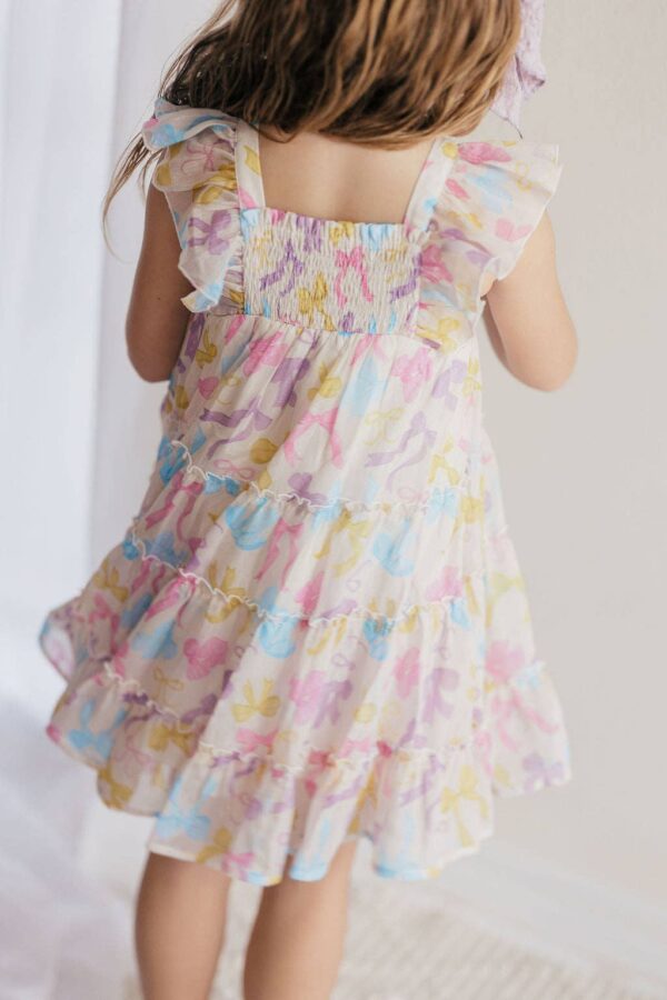 Child wearing colorful floral dress, back view.