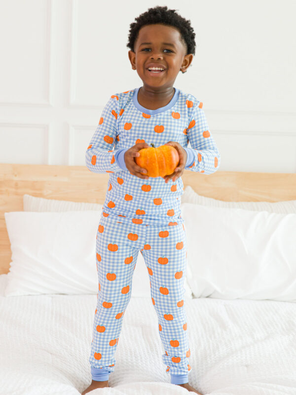 Child in pumpkin pajamas holding a small pumpkin