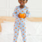 Child in pumpkin pajamas holding a small pumpkin