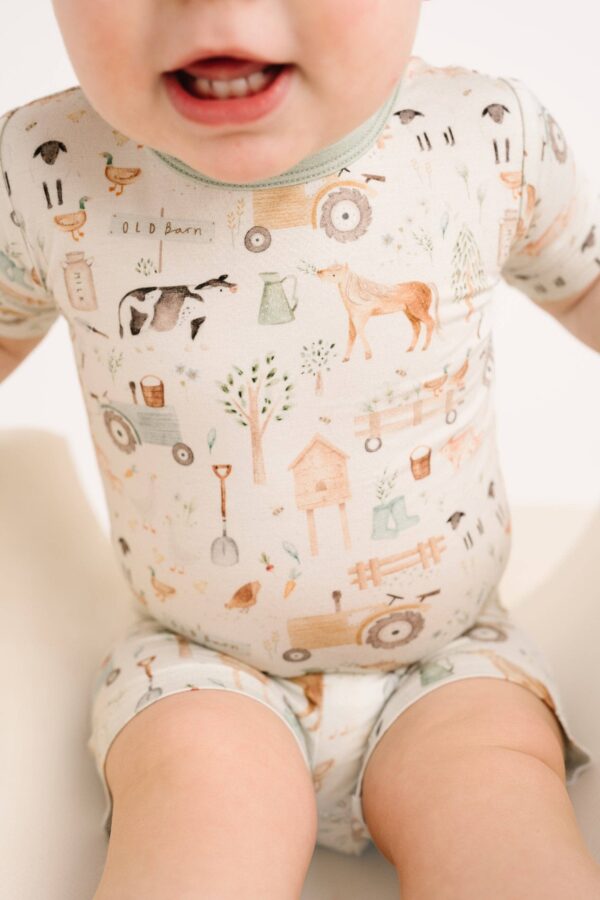 Baby wearing farm-themed patterned romper