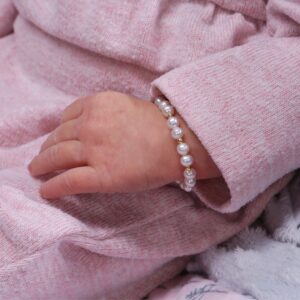 Baby wearing pearl bracelet on pink outfit