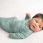 Newborn baby in blue sleeping on white blanket.