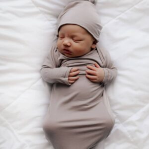 Newborn baby sleeping wrapped in gray blanket.