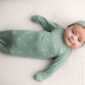 Baby in green outfit lying on blanket