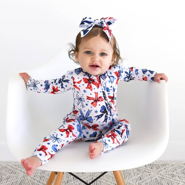 gigi and max eleanor bow clip bow 4th of july hair accessory Baby in festive outfit on white chair smiling.