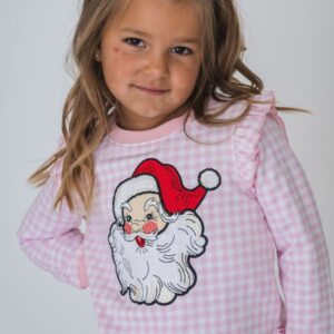 Child wearing Santa-themed sweater, smiling confidently.