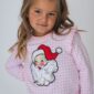 Child wearing Santa-themed sweater, smiling confidently.
