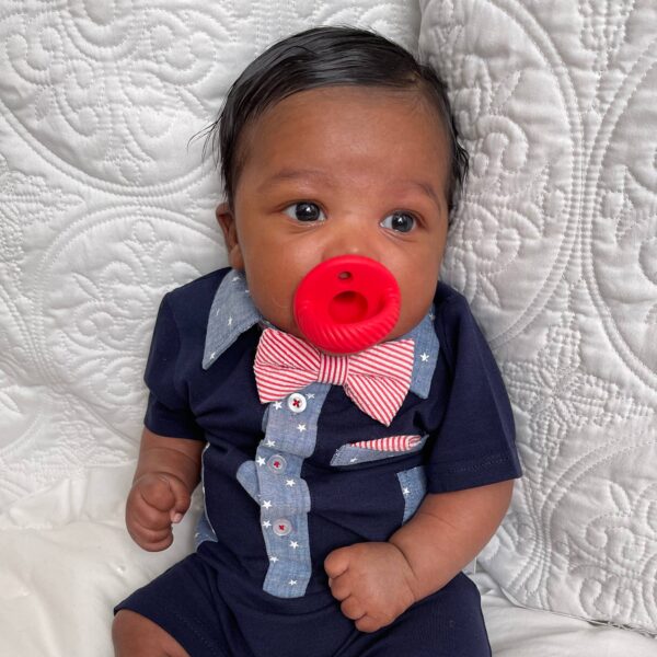 itzy ritzy sweetie soother™ pacifier sets (2 pack): aquamarine + peach bows Baby in navy outfit with red pacifier