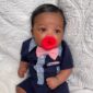 Baby in navy outfit with red pacifier