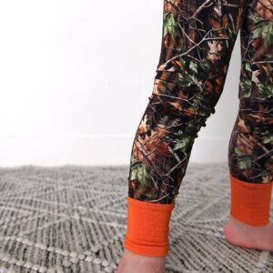 Child in camouflage leggings with orange cuffs.