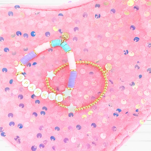 bits & bows sparkle heart purse Colorful beaded bracelets on pink sequin background.