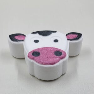 Cow-shaped bath bomb with pink and black details.
