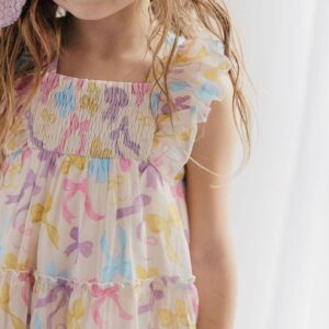 Child wearing colorful, ruffled dress with bows.