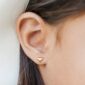 Gold heart-shaped earring in woman's ear